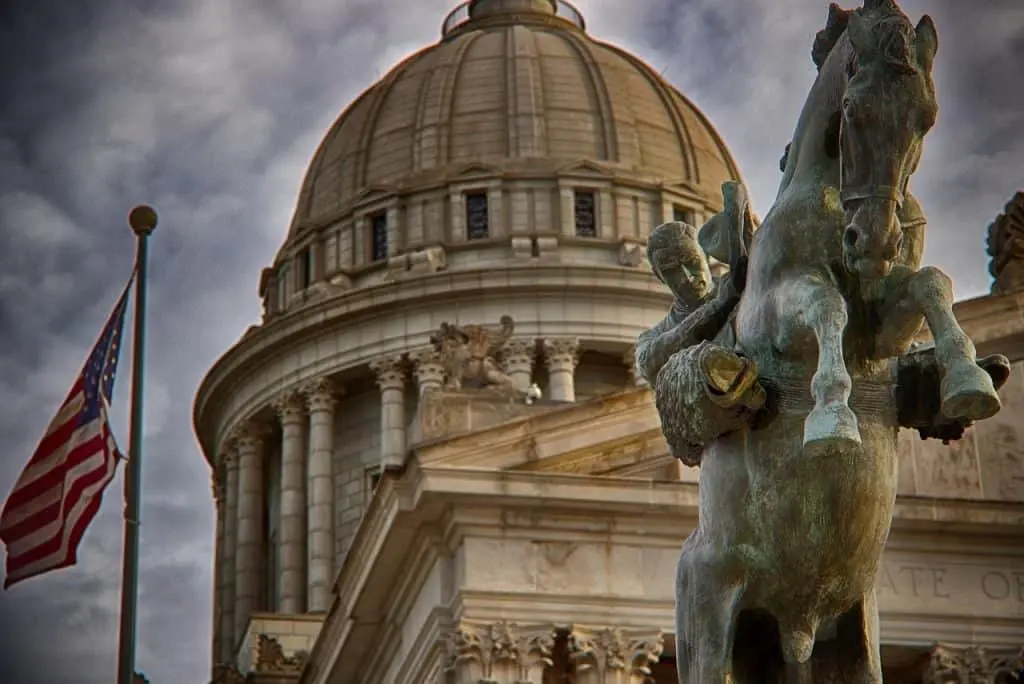 Image of the state capital building, a flag, and a statue in Oklahoma