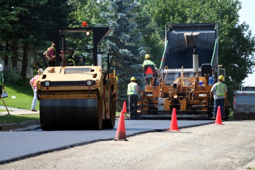Image of a group of men laying asphalt who use answering services for paving companies