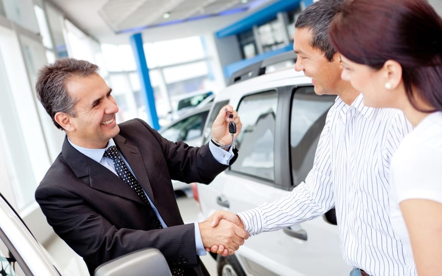 Image of a car salesman selling a vehicle while the car dealership answering service covers the phones
