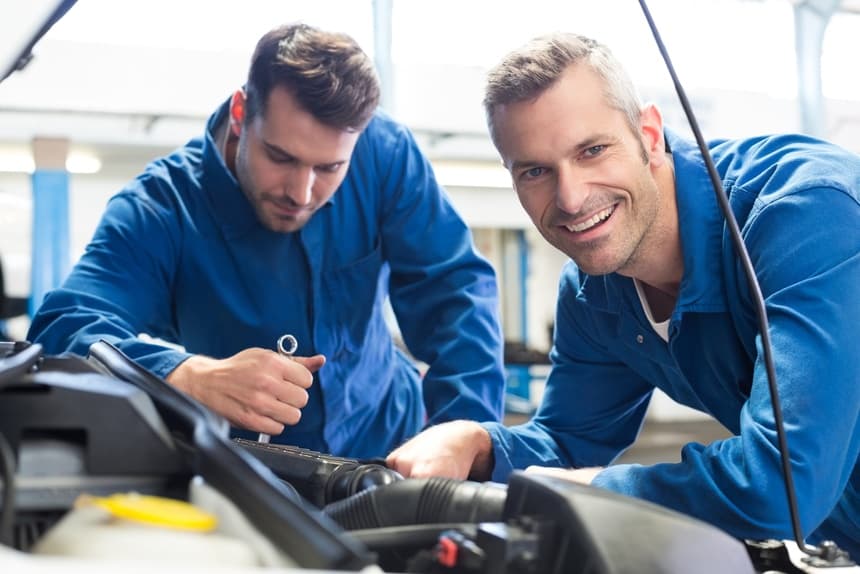 Image of two men working on a car that use a call center for automotive services