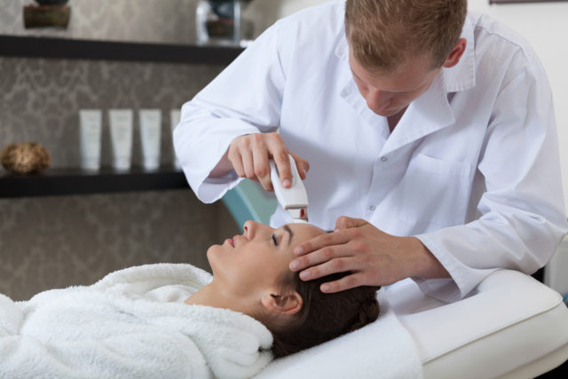 Image of a dermatologist with a patient while his dermatology answering service handles phone calls