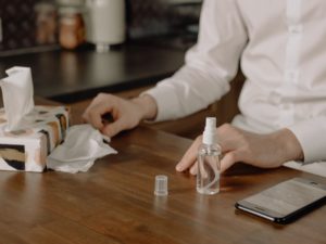 person with tissues, sanitizer, and a cell phone