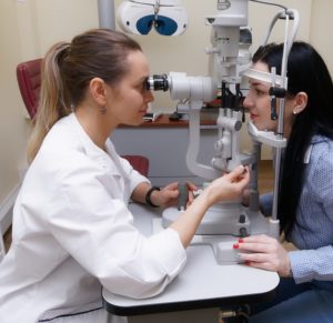 image of an eyecare professional giving an exam while an optometry receptionist service answers phone calls