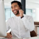 man smiling while taking a phone call in a call center