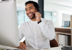 man smiling while taking a phone call in a call center