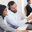 two call center agents discussing a call while looking at a computer