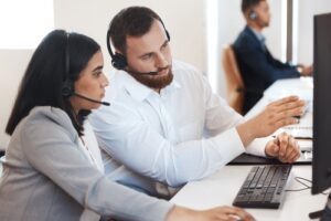 two call center agents discussing a call while looking at a computer