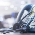 image of call center phone with headset resting on it