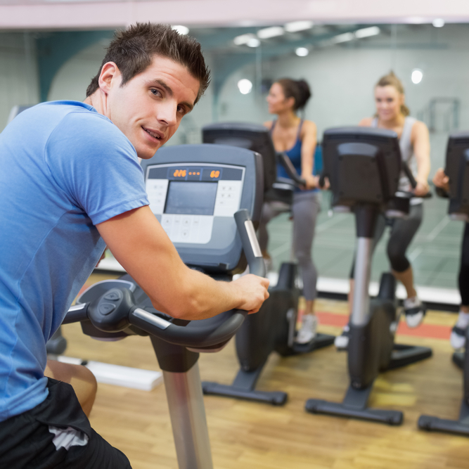Image of a man leading a fitness class while the gym answering service handles phone calls