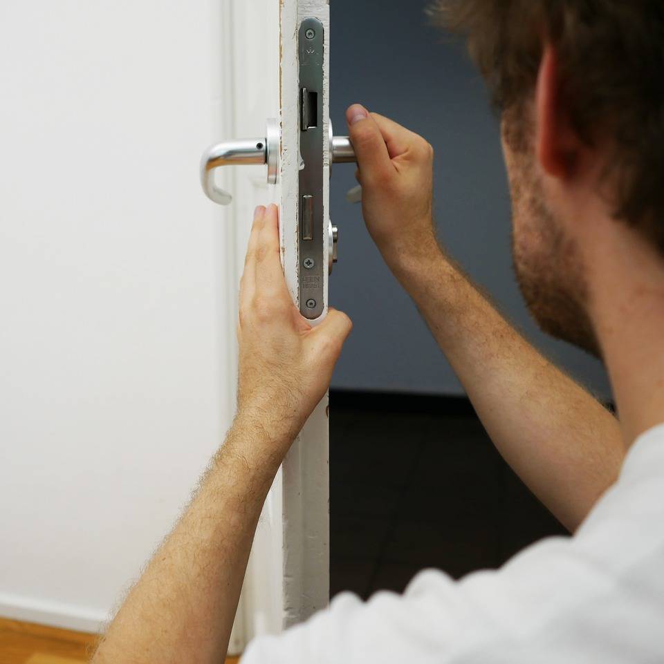 man working on a door who uses an answering service for locksmiths