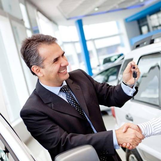 Image of a car salesman selling a vehicle while the car dealership answering service covers the phones