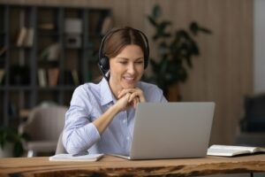 woman with headset on at desk looking at her laptop